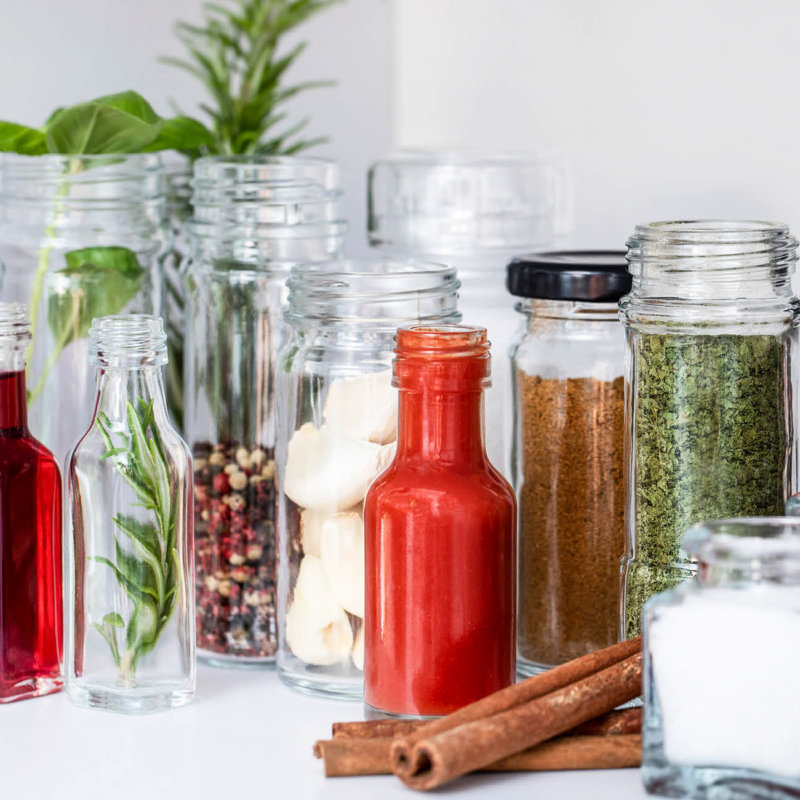 Selection of filled spice jars and hot sauce bottles