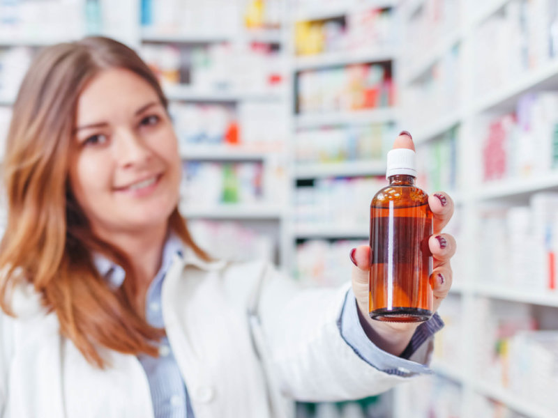 Pharmacist holding filled brown bottle