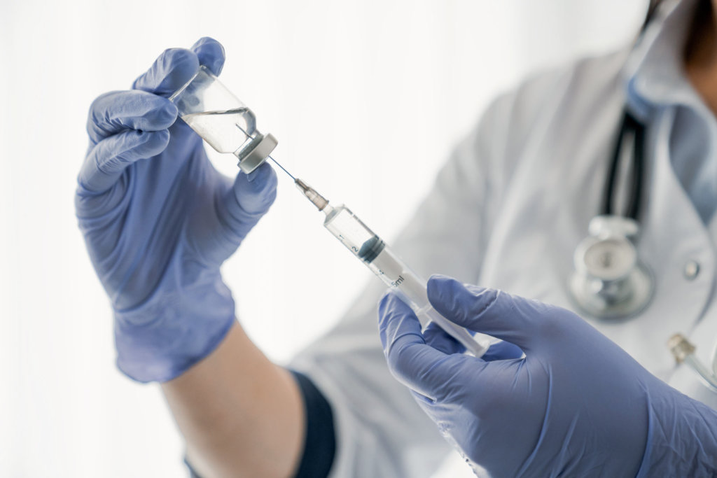 doctor draws up syringe from injection vial