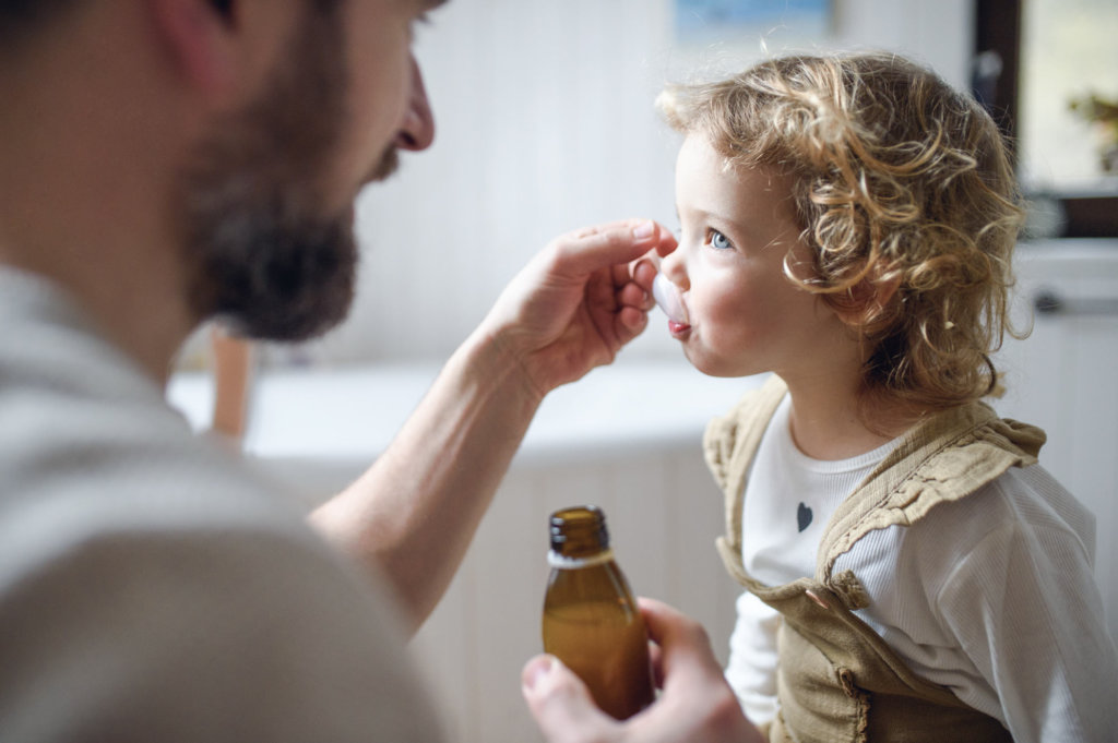 Father gives daughter antibiotics with spoon