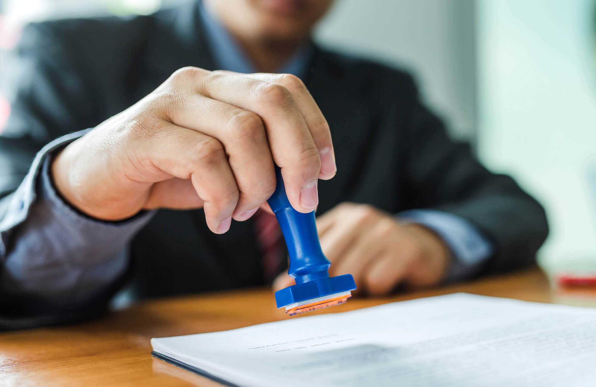 Person at desk holding a stamp