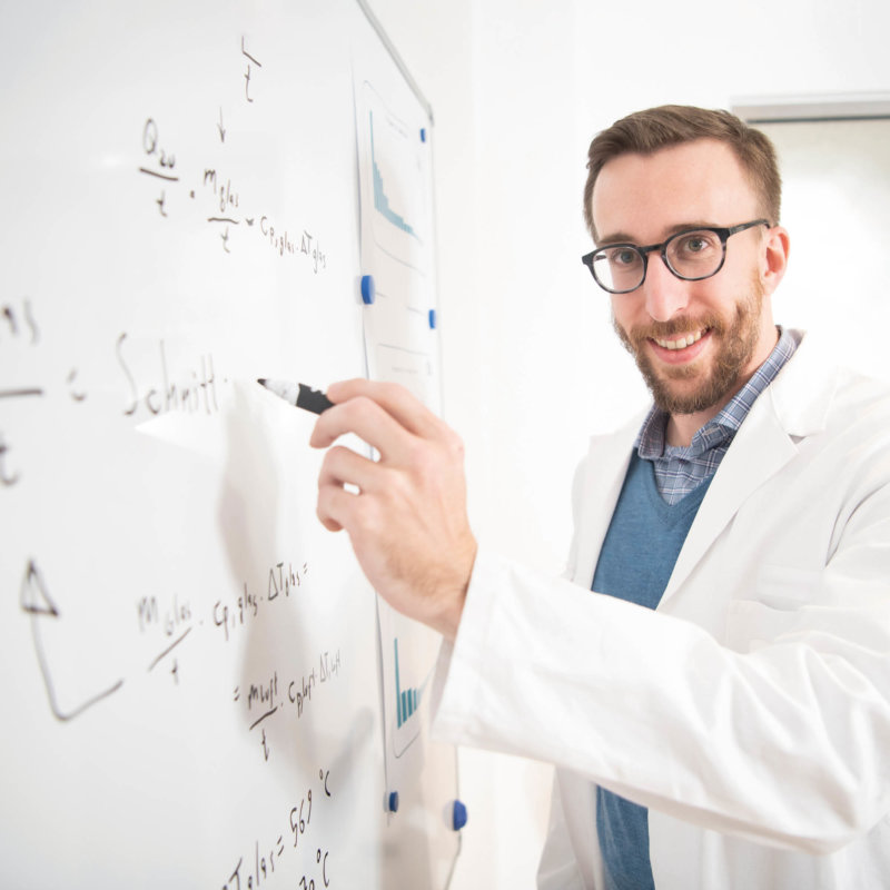 Research employee writing formulas on whiteboard