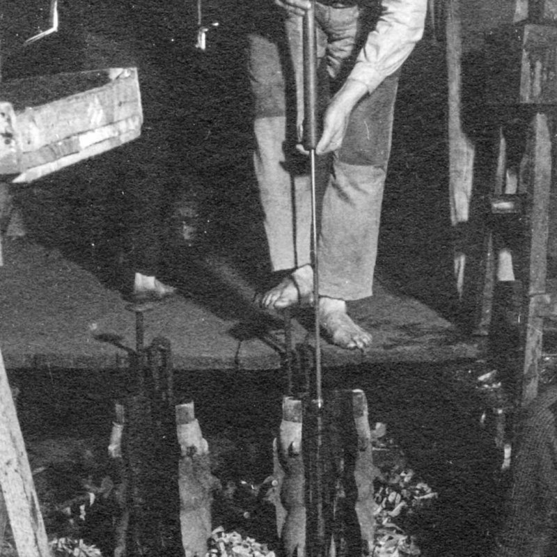 Historic picture of glass maker mouth blowing an item into the mould