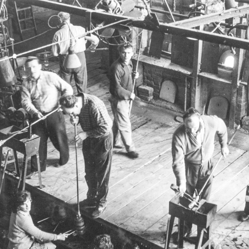 Historic picture of several glass  makers on working stage in mouthblowing glass production