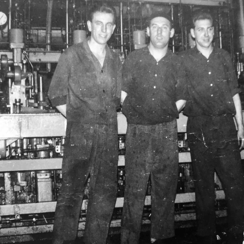 Historic picture of 3 machine operators in front of IS machine