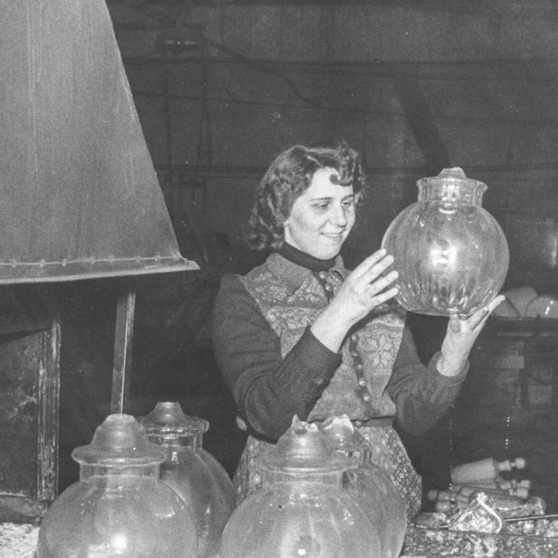 Historic picture of woman checking mouthblown glass lamps